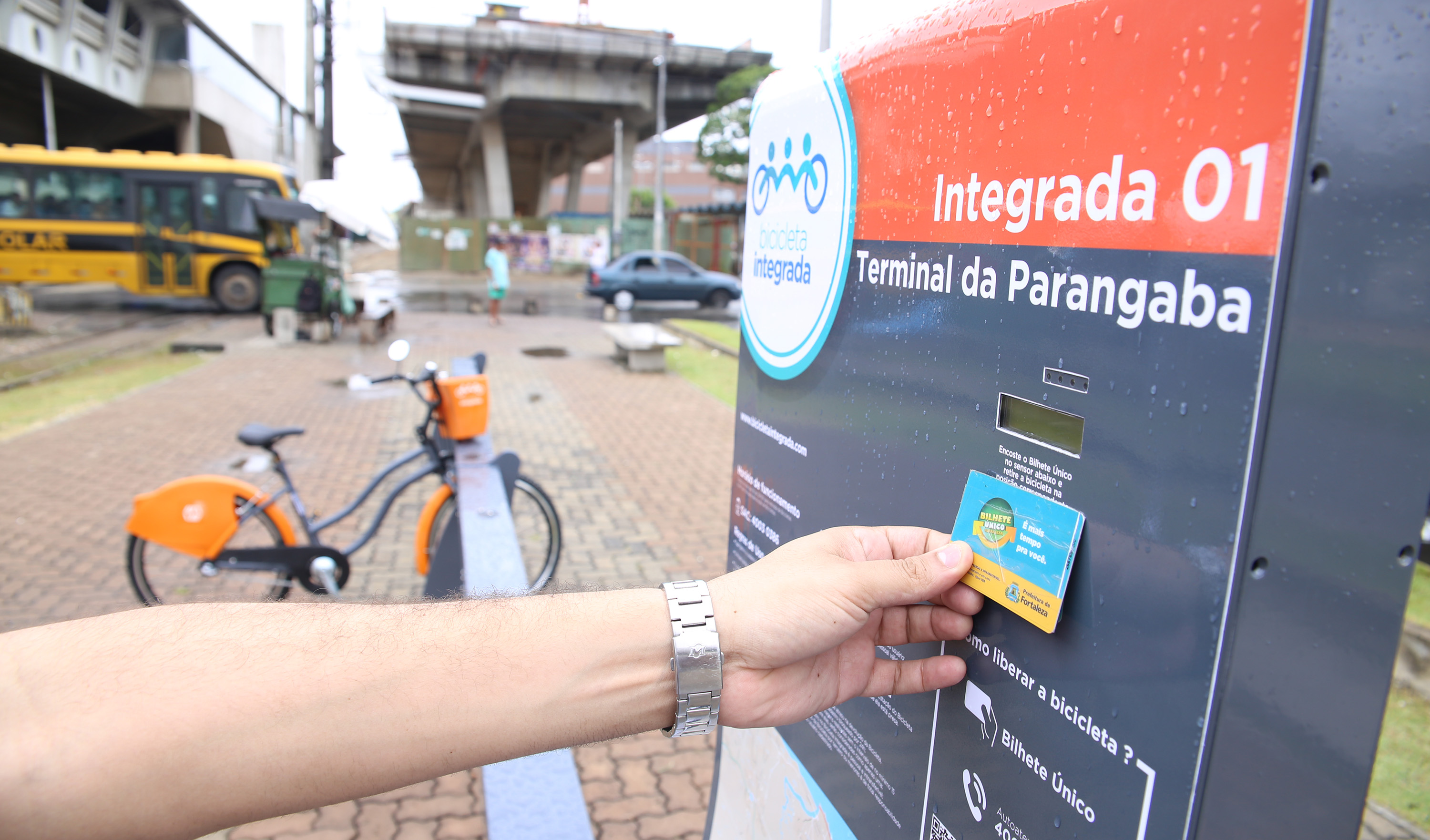 braço de uma pessoa passando o bilhete único em máquina de estação de bicicleta compartilhada